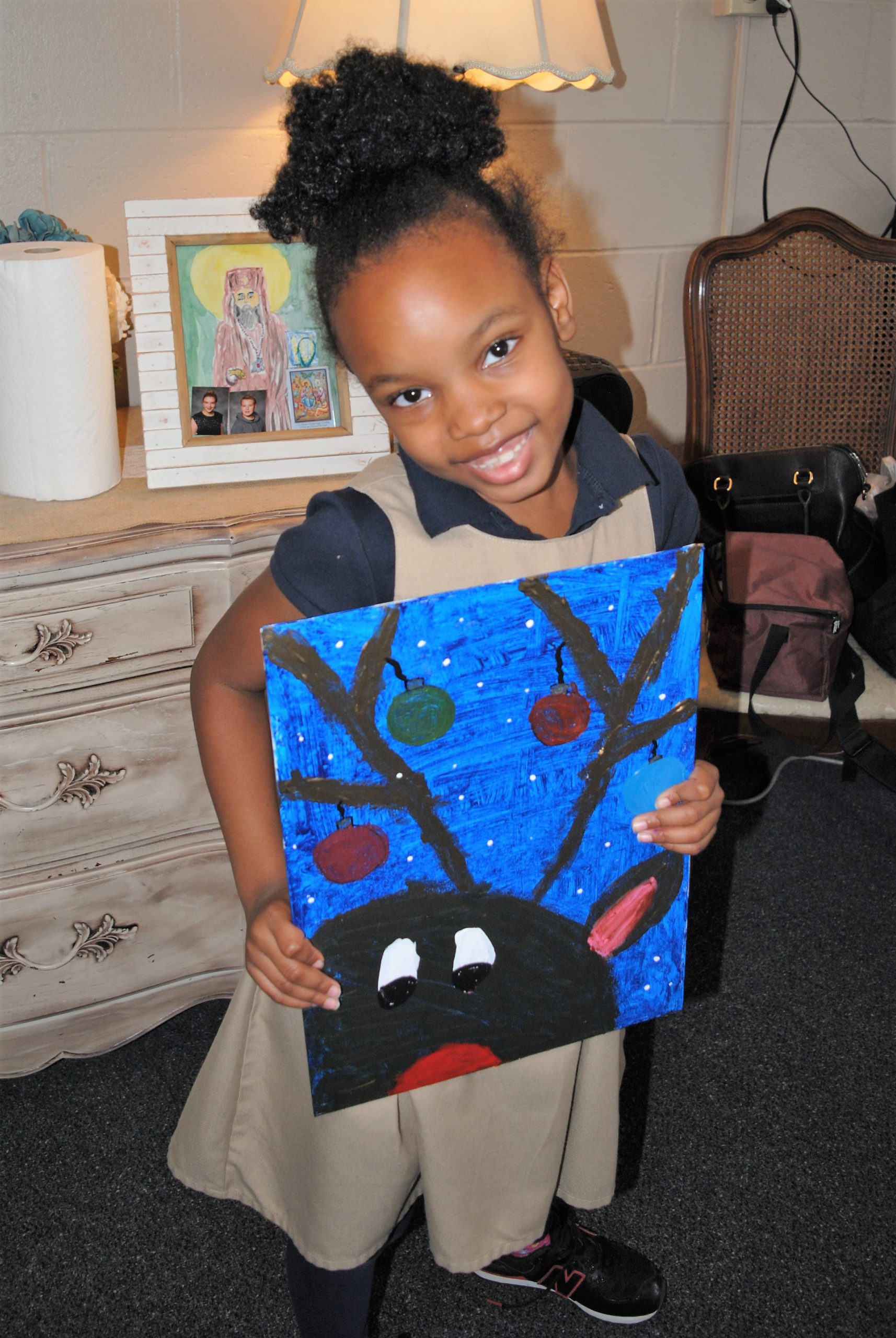 Student holds her hand-painted reindeer picture